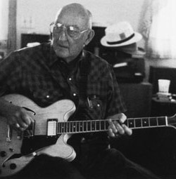 Lynn Holsclaw holds his hollowbody electric guitar at a session in Dwight Lamb’s music room. Mark Wilson photo.