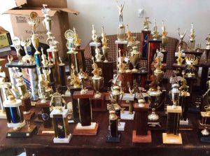 A tabletop covered in trophies from fiddle contests