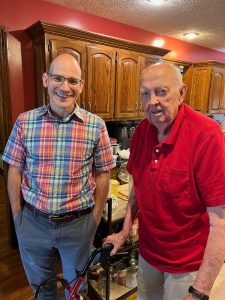 Two men pose for a photo in a kitchen